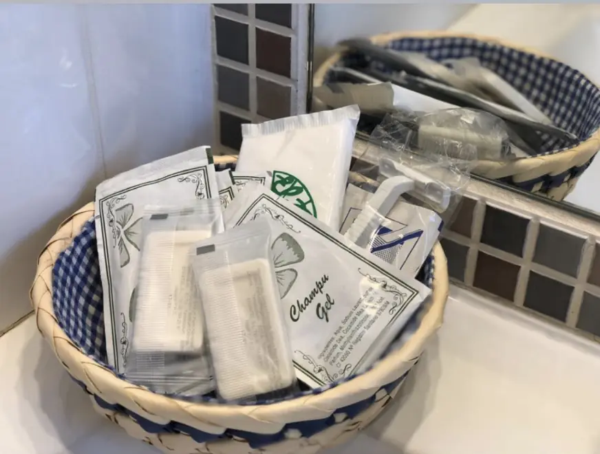 Cesta con artículos de aseo en el baño de la habitación