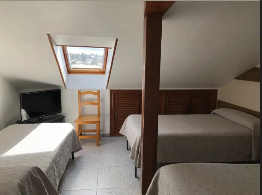 Habitación abuhardillada con vigas de madera y ventana al pueblo